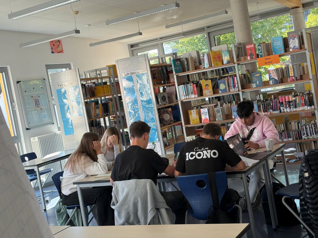 Schüler:innen arbeiten in der Schulbibliothek der Gesamtschule am Rosenberg an ihren Präsentationen